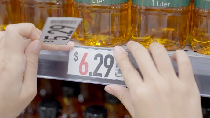 Retail worker replacing product price label with new lower price
